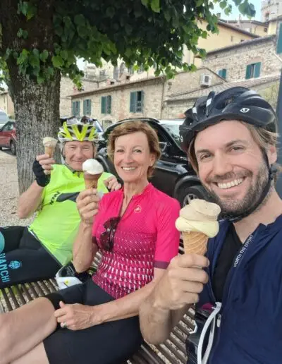 Drie fietsers eten ijsjes op een bankje op een Italiaans dorpsplein