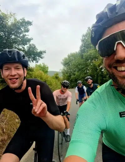 Selfie van twee fietsers met peace-teken, achter hen rijdt de groep