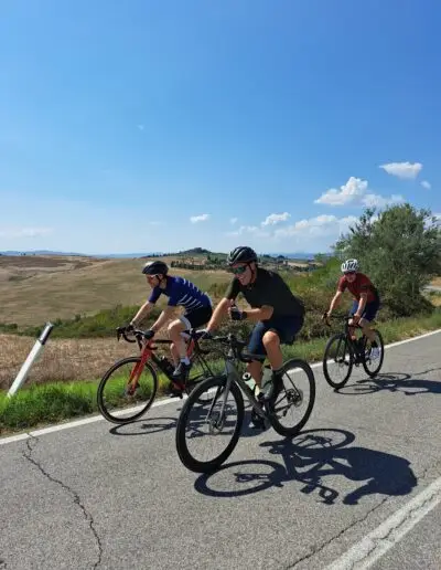 Drie fietsers naast elkaar op een weg door de Toscaanse heuvels