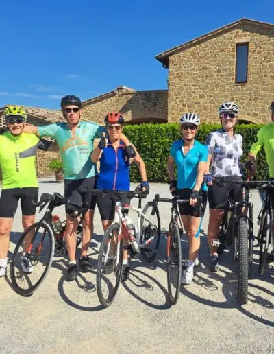 Zes fietsers poseren voor een Toscaanse boerderij van natuursteen