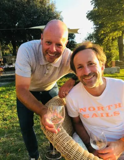 Twee mannen proosten met witte wijn in een zonnige tuin
