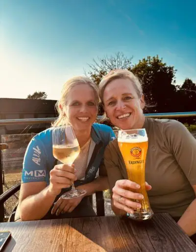 Twee vrouwen proosten met wijn en weizenbier op een terras in avondzon
