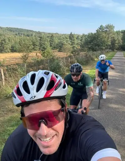 Drie fietsers op een fietspad door de heide, gezien vanaf de voorste rijder